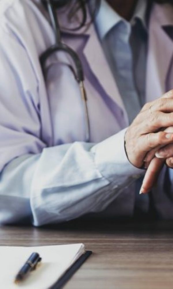 Happy patient is holding caregiver for a hand while spending time together. Elderly woman in nursing home and nurse..