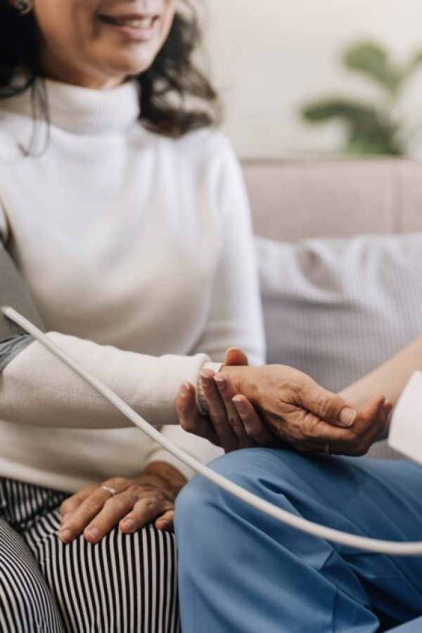 Happy senior woman having her blood pressure measured in a nursing home by her caregiver. Happy nurse measuring blood pressure of a senior woman in living room..